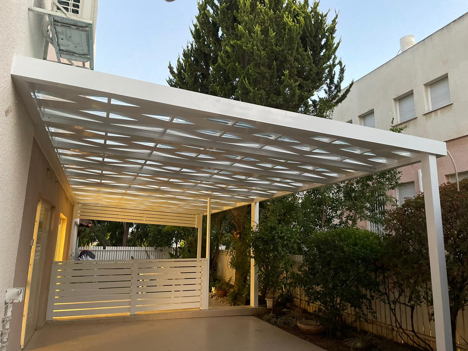 White aluminum carport with matching privacy fence at dusk